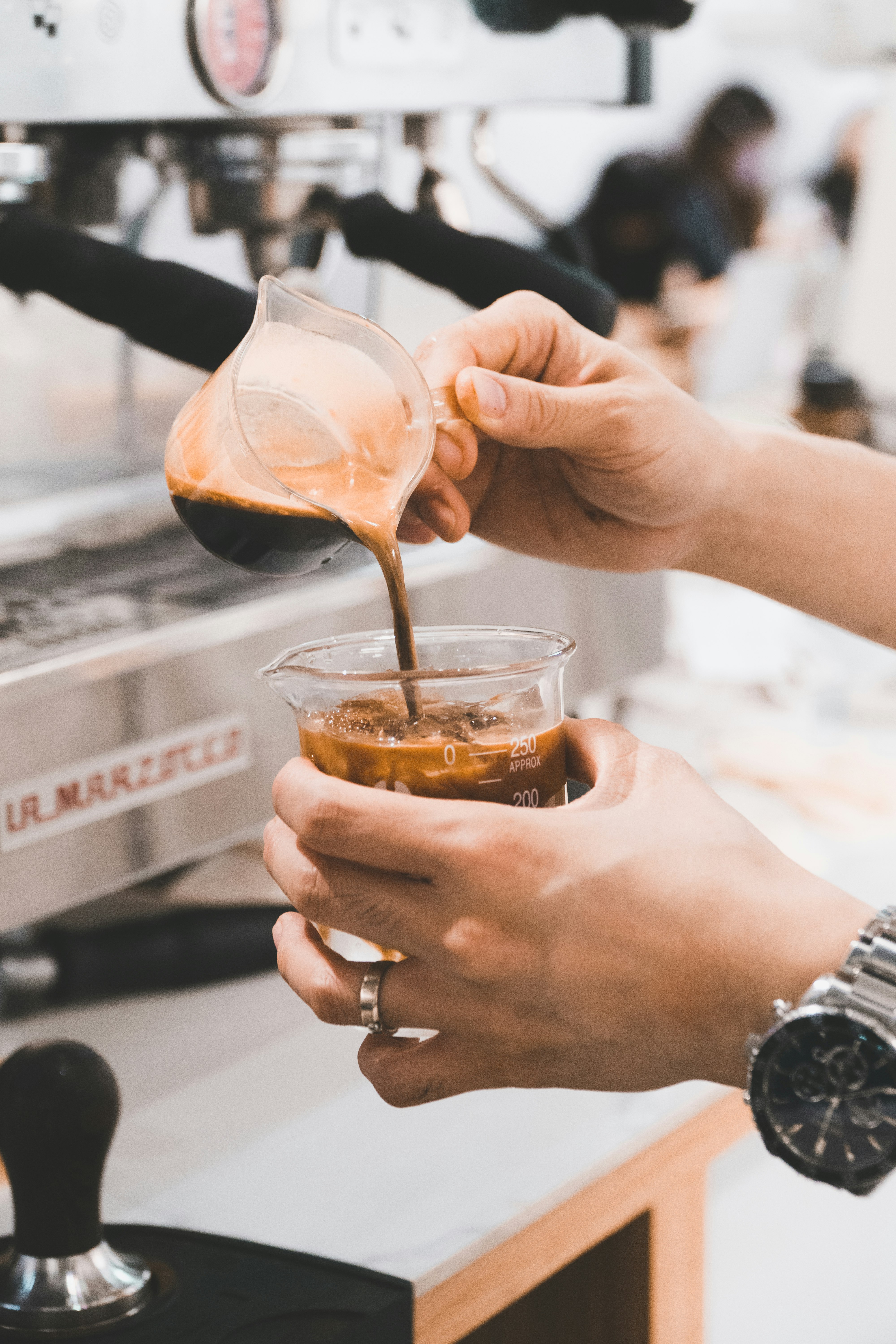 person pouring brown liquid on clear plastic cup